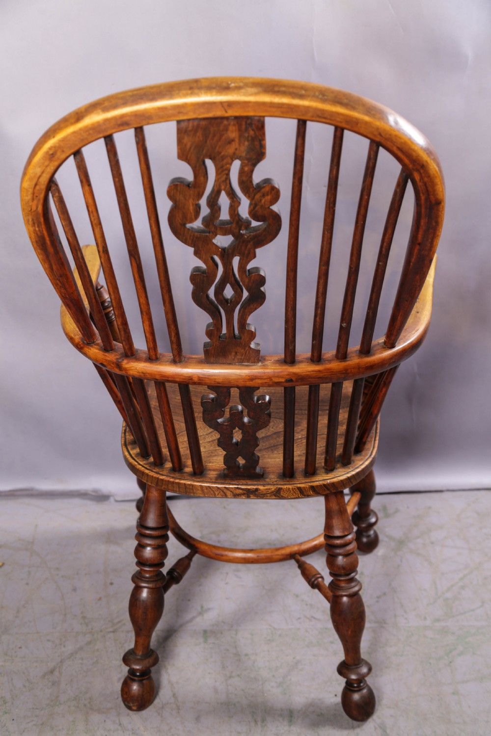 A 19th-century yew wood Windsor armchair featuring a bow back, ornate pierced splat, turned spindles, shaped seat, and turned legs. View V