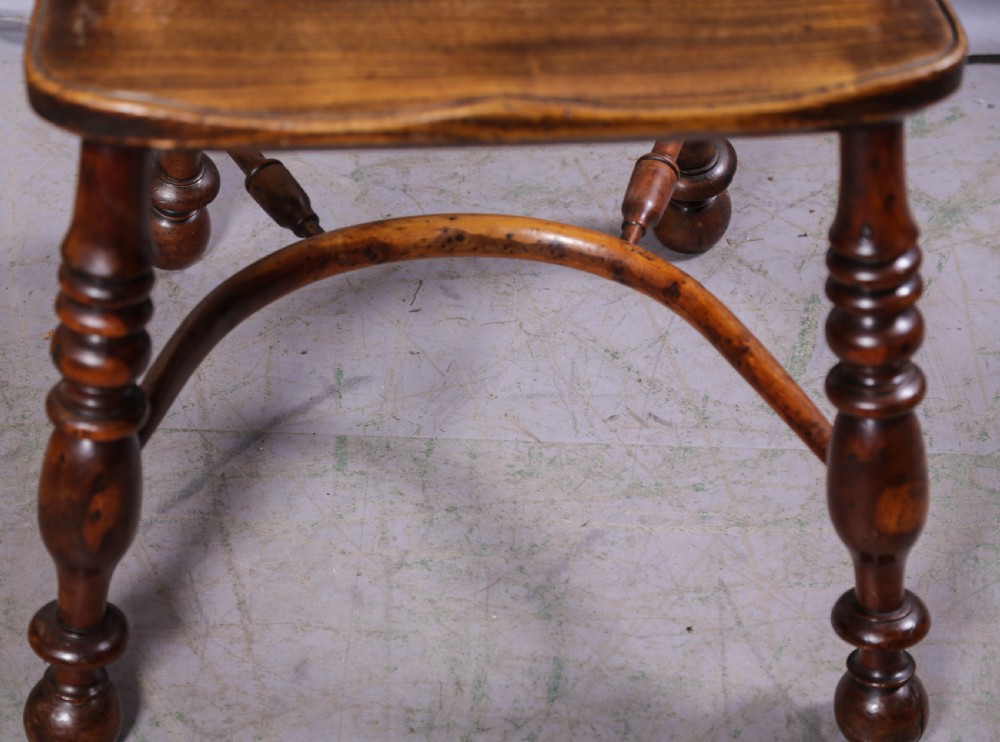 A 19th-century yew wood Windsor armchair featuring a bow back, ornate pierced splat, turned spindles, shaped seat, and turned legs. View VI