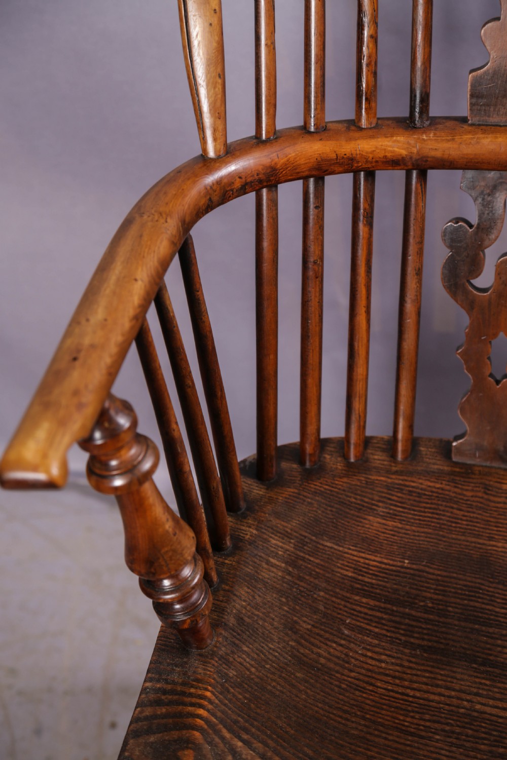 An antique yew wood high-back Windsor armchair featuring a pierced decorative splat, spindle back, shaped elm seat, turned legs, and a curved stretcher. View V