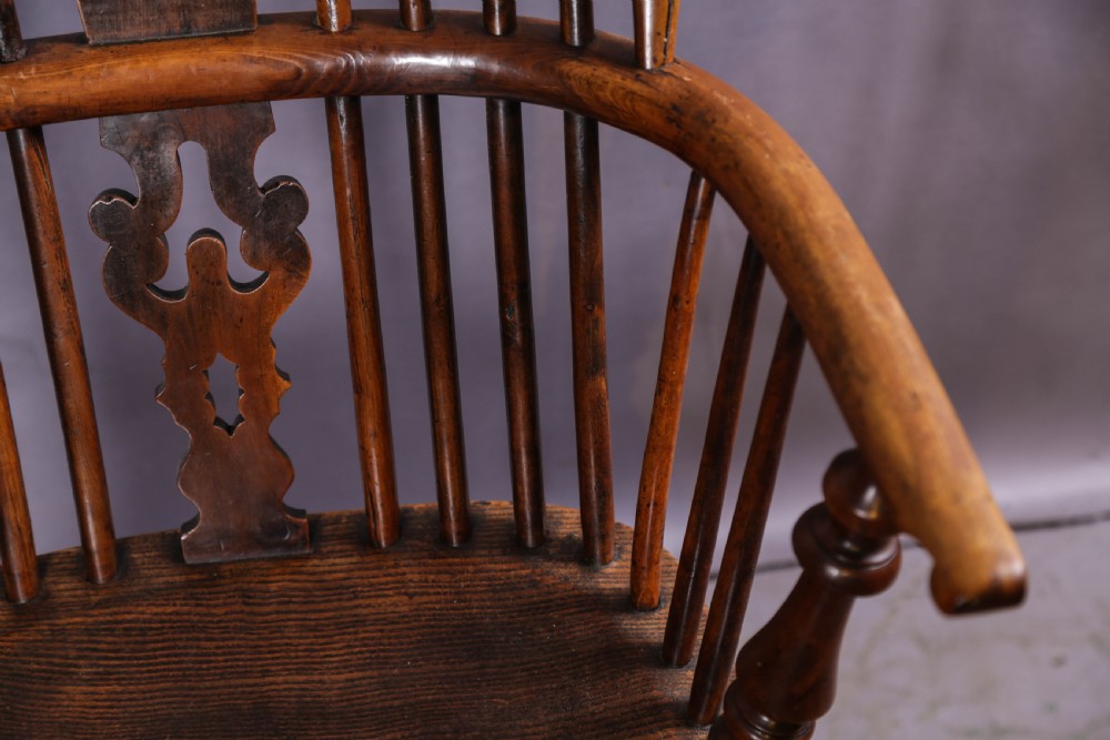 An antique yew wood high-back Windsor armchair featuring a pierced decorative splat, spindle back, shaped elm seat, turned legs, and a curved stretcher. View VI