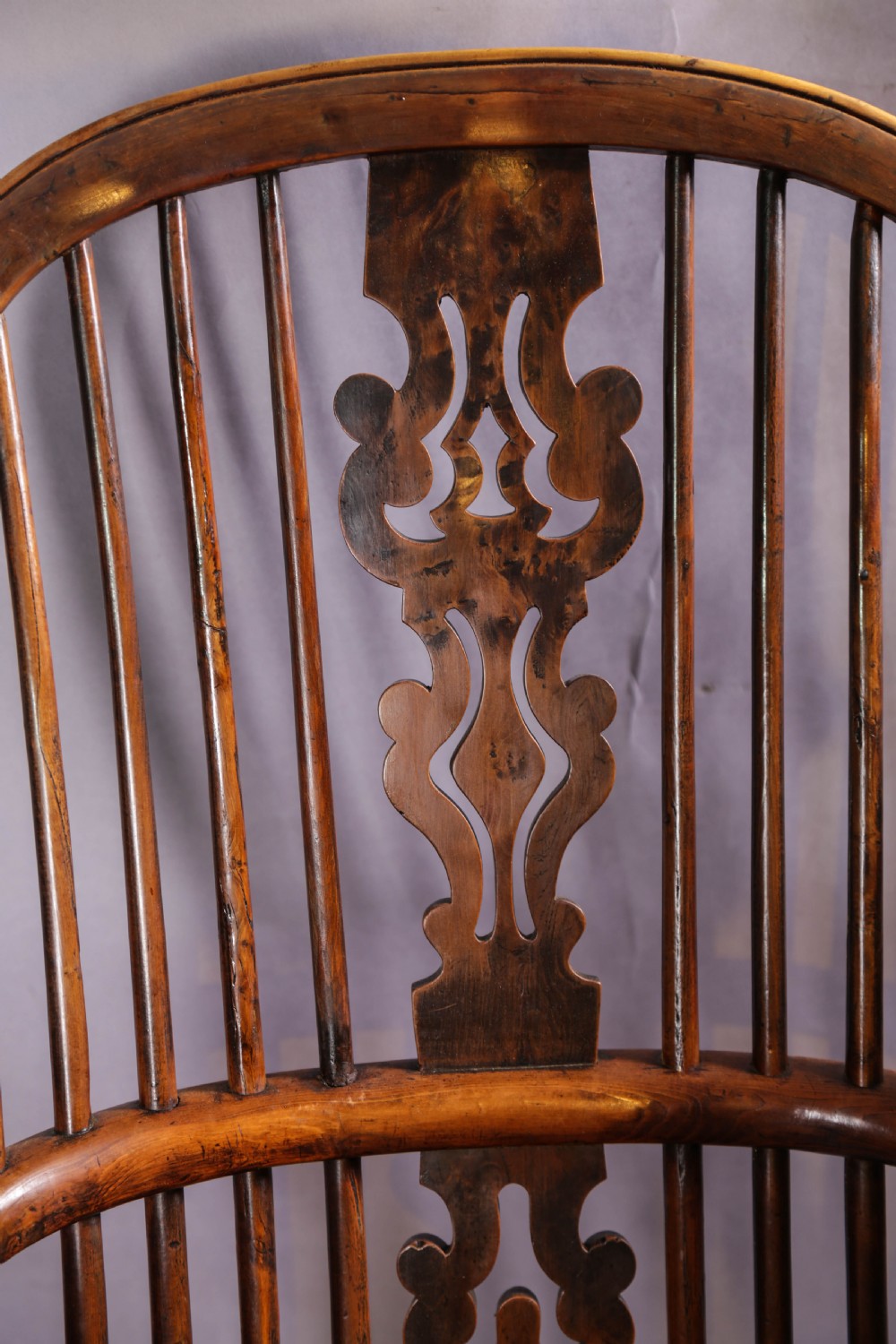 An antique yew wood high-back Windsor armchair featuring a pierced decorative splat, spindle back, shaped elm seat, turned legs, and a curved stretcher. View VIII
