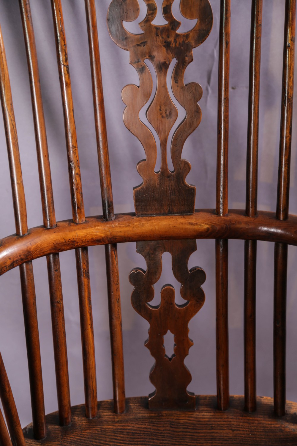 An antique yew wood high-back Windsor armchair featuring a pierced decorative splat, spindle back, shaped elm seat, turned legs, and a curved stretcher. View IX