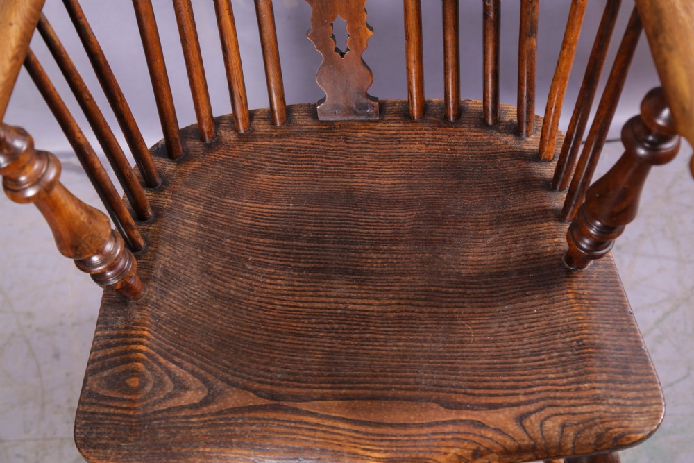 An antique yew wood high-back Windsor armchair featuring a pierced decorative splat, spindle back, shaped elm seat, turned legs, and a curved stretcher. View X