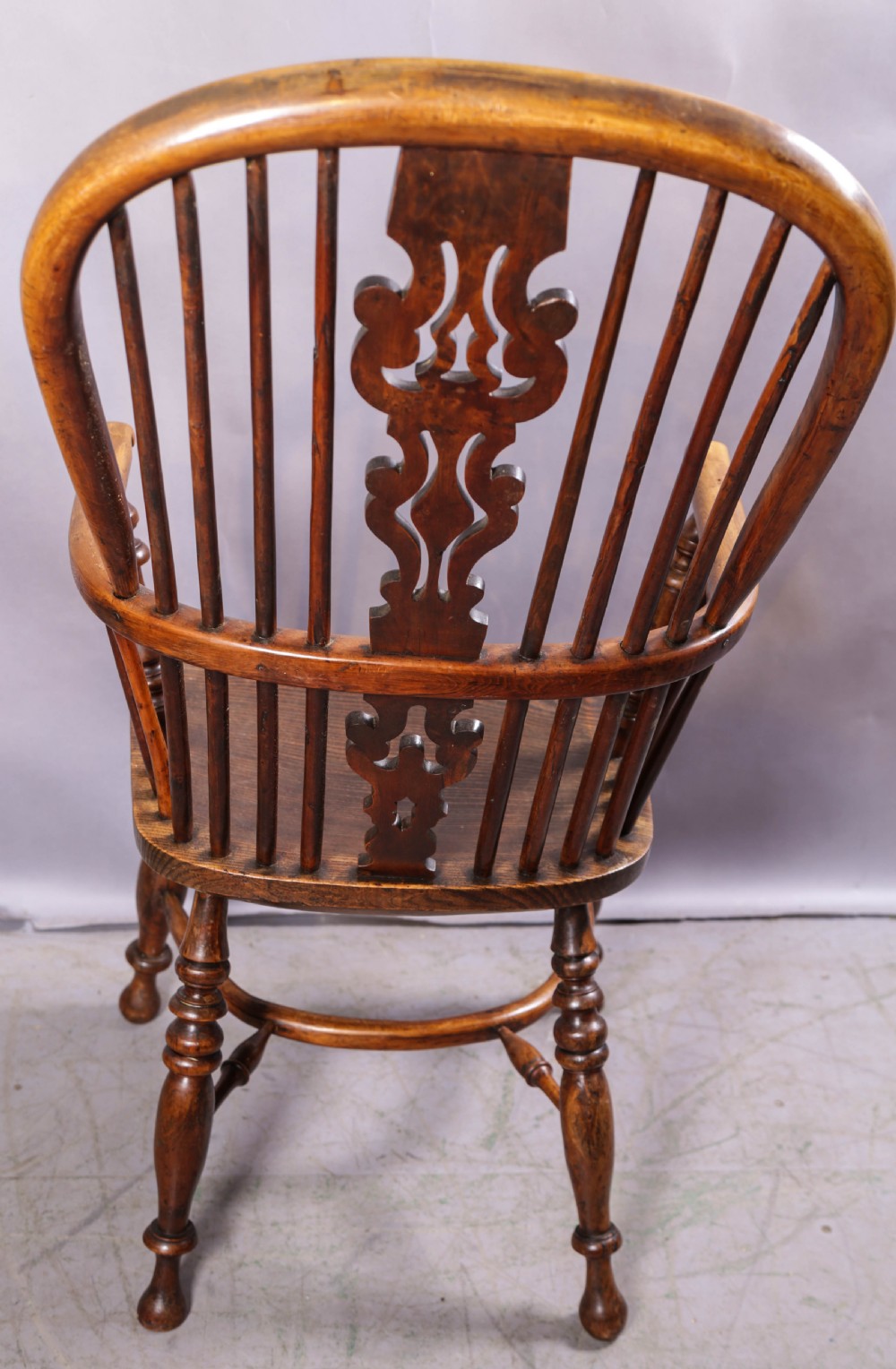 An antique yew wood high-back Windsor armchair featuring a pierced decorative splat, spindle back, shaped elm seat, turned legs, and a curved stretcher. View XIII