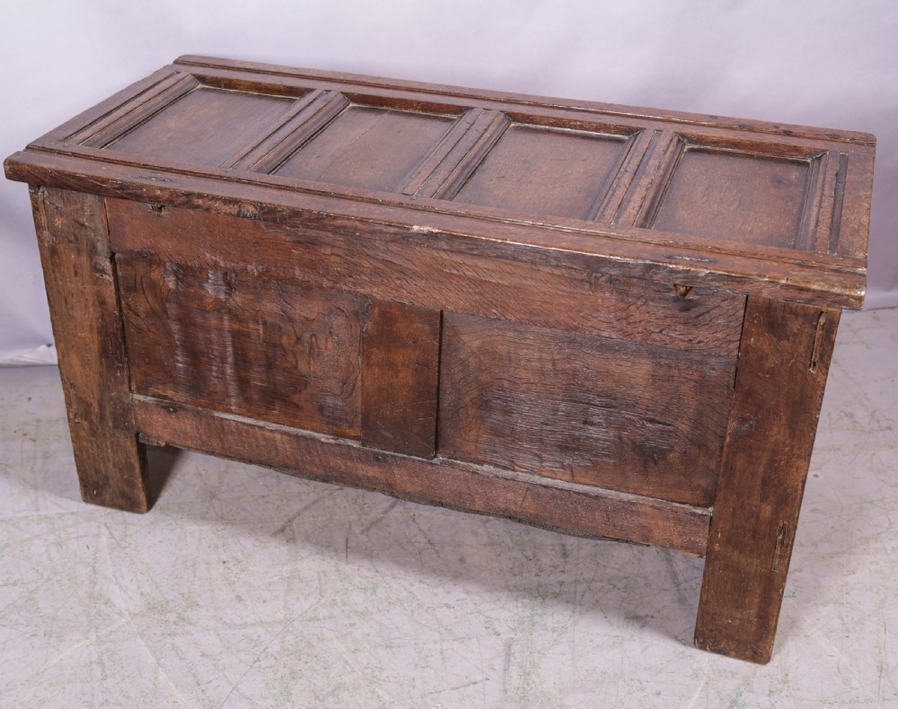 A 17th-century carved dark oak coffer featuring a four-panel hinged lid, a carved lunette frieze, three front panels, and a central iron escutcheon. View IX