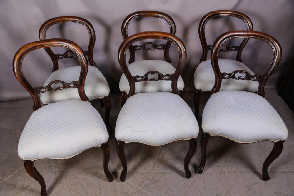 A set of six dark mahogany Victorian dining chairs featuring rounded balloon backrests with carved mid-rails and light-coloured patterned upholstered seats.