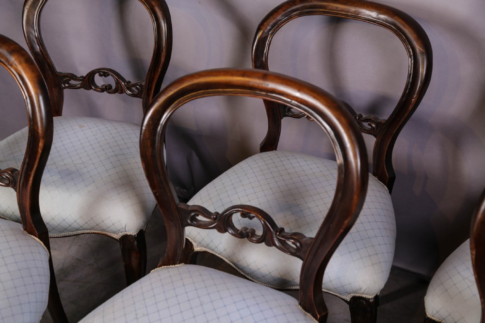 A set of six dark mahogany Victorian dining chairs featuring rounded balloon backrests with carved mid-rails and light-coloured patterned upholstered seats. View VII