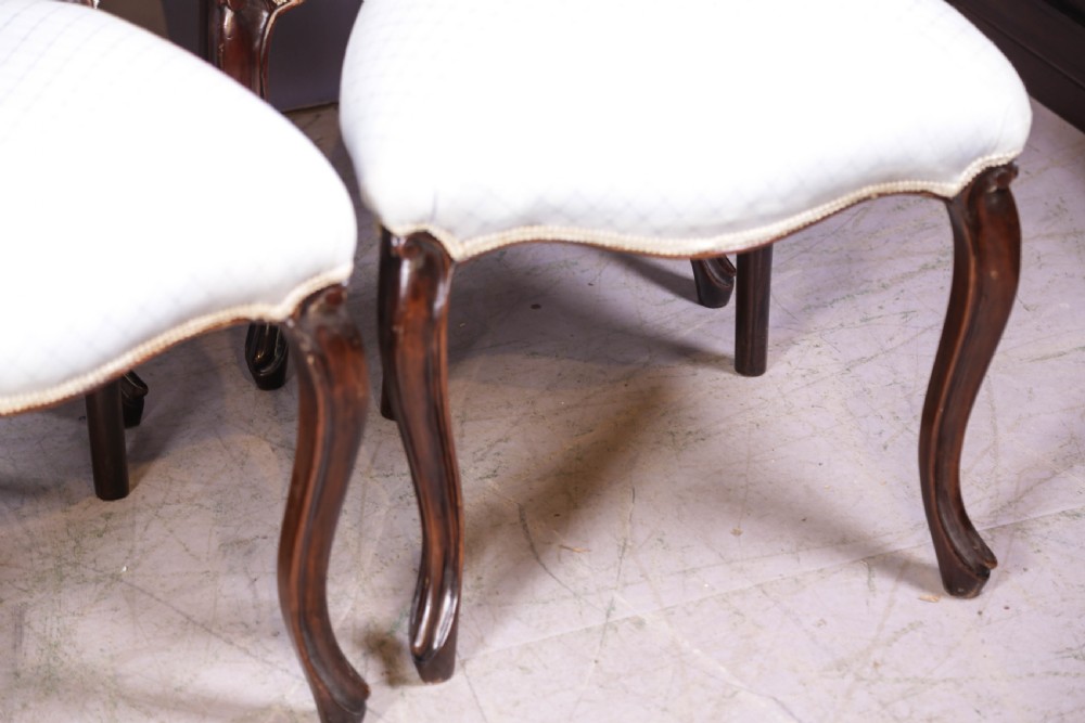 A set of six dark mahogany Victorian dining chairs featuring rounded balloon backrests with carved mid-rails and light-coloured patterned upholstered seats. View X