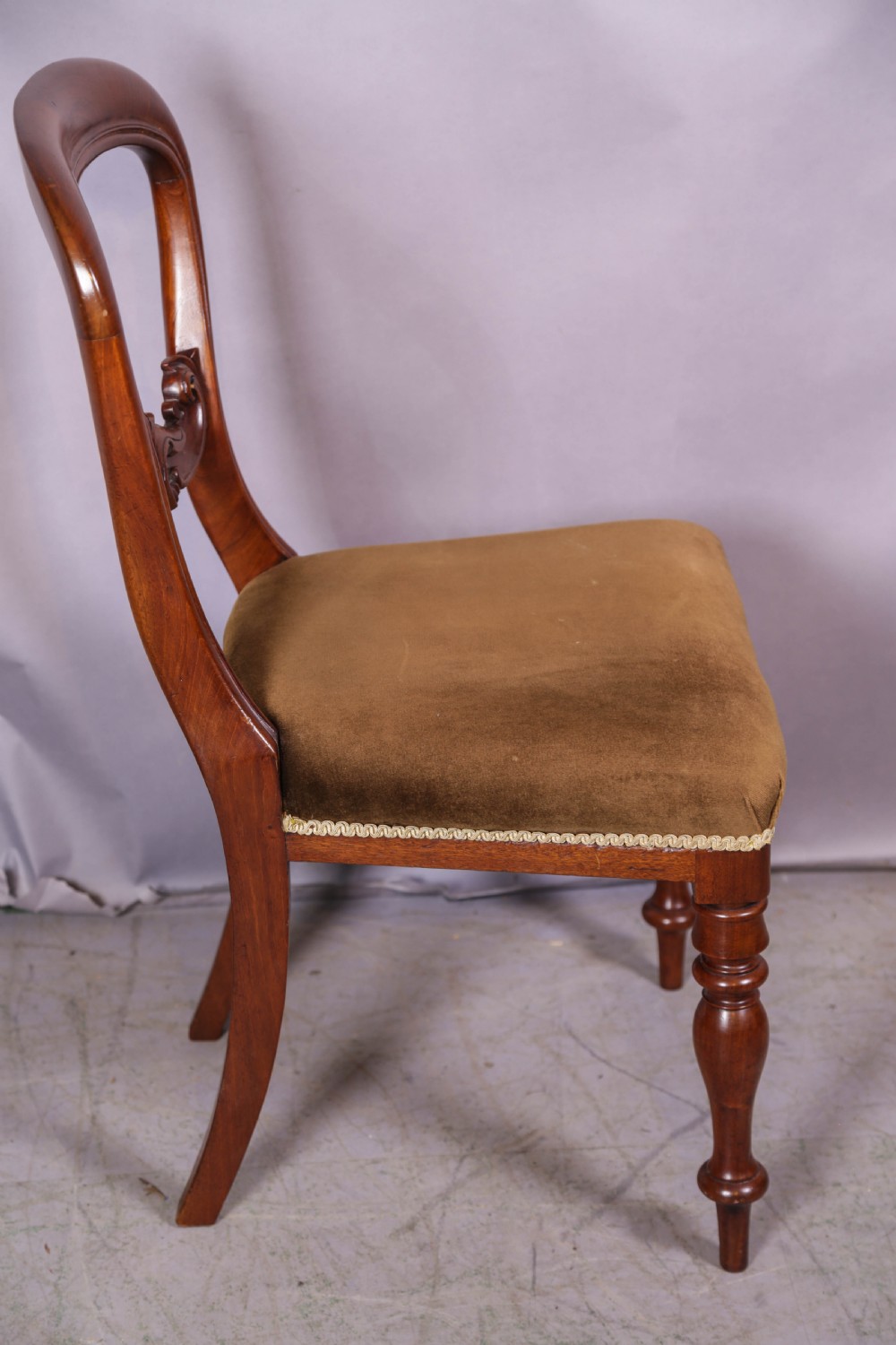 Set of four Victorian mahogany balloon back dining chairs featuring carved horizontal mid-rails, turned front legs, and brown velvet upholstered seats. View VI