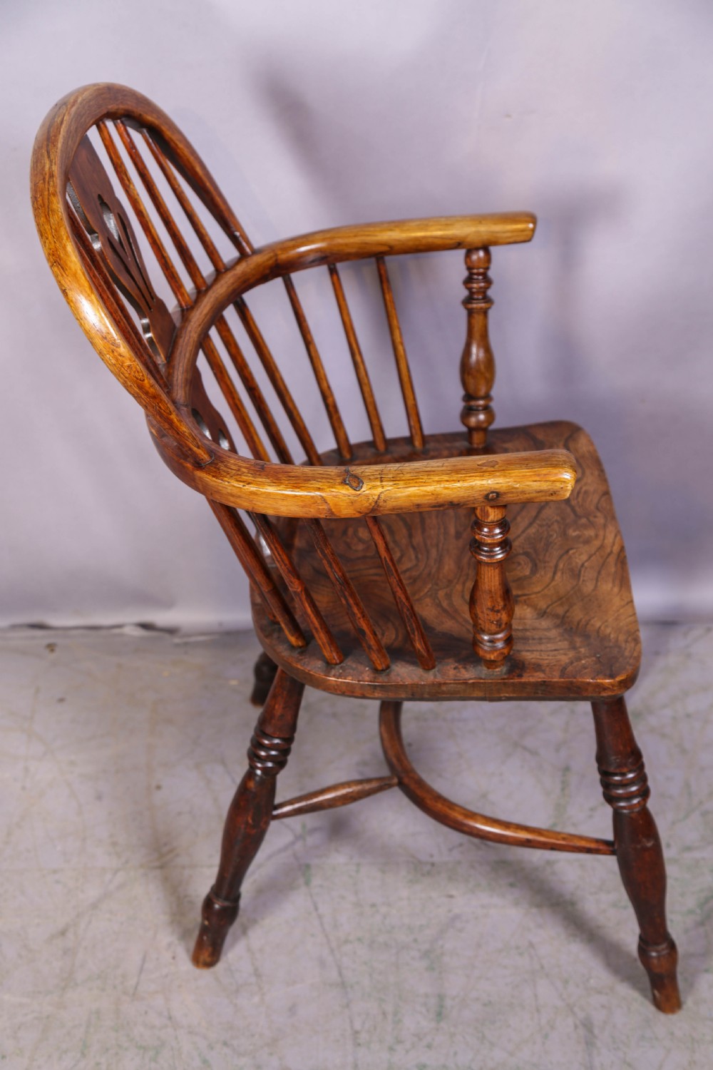 A low back ash and elm Windsor armchair featuring a shaped solid elm saddle seat, turned legs, curved stretcher, and a pierced splat back. View II