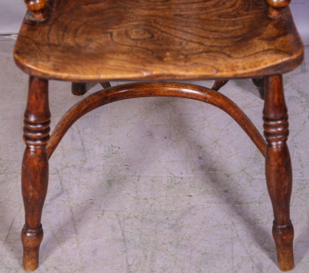 A low back ash and elm Windsor armchair featuring a shaped solid elm saddle seat, turned legs, curved stretcher, and a pierced splat back. View III