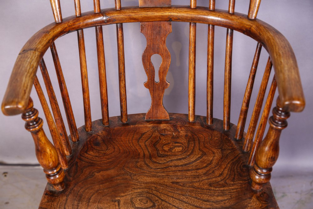 A low back ash and elm Windsor armchair featuring a shaped solid elm saddle seat, turned legs, curved stretcher, and a pierced splat back. View IV