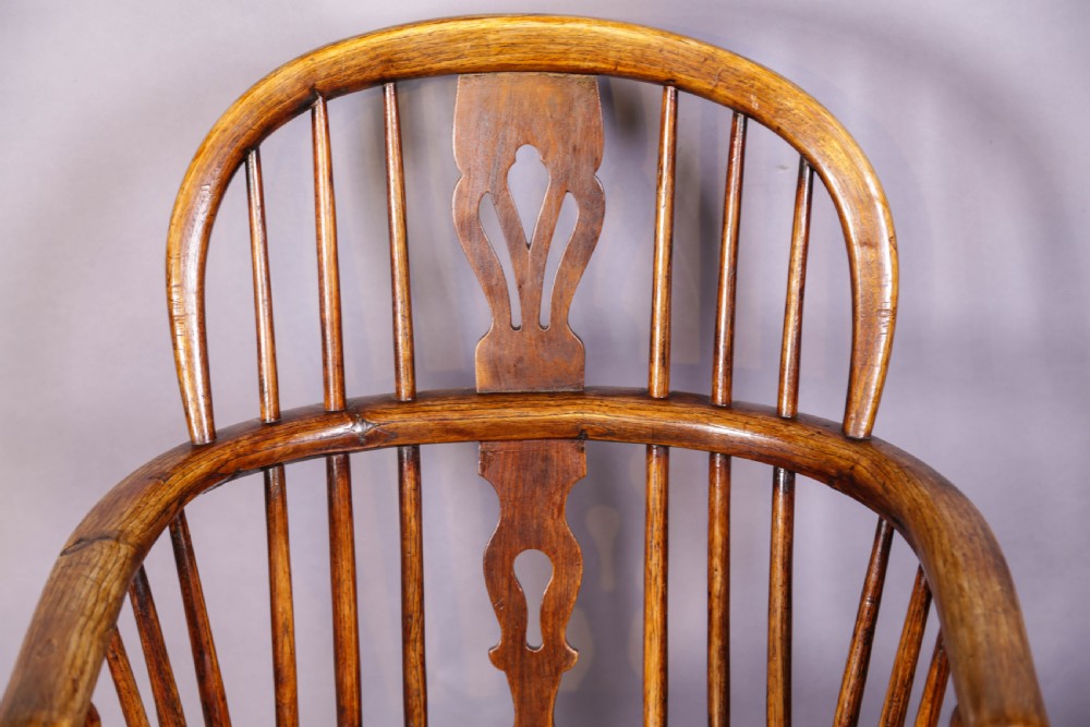 A low back ash and elm Windsor armchair featuring a shaped solid elm saddle seat, turned legs, curved stretcher, and a pierced splat back. View V