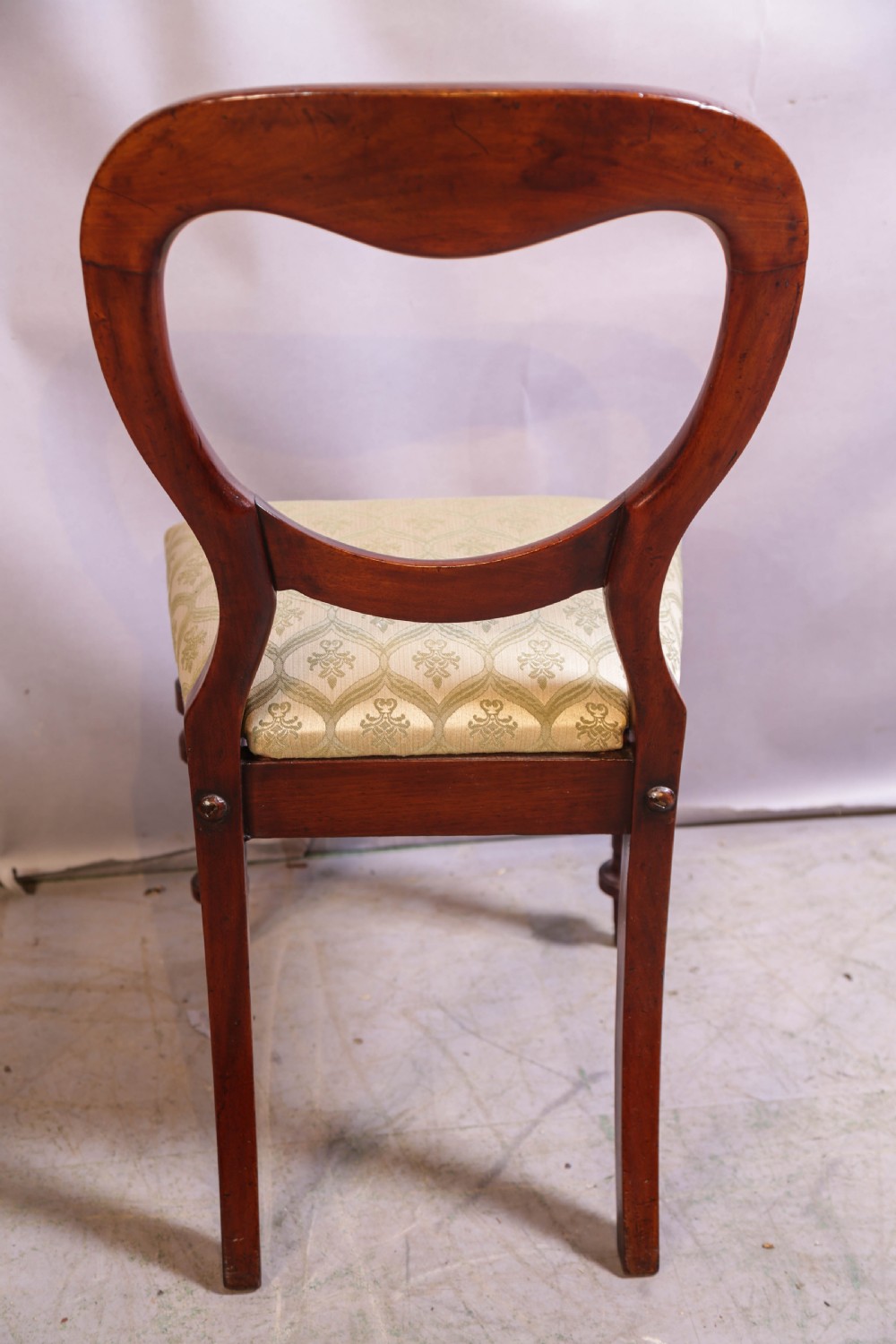 Set of eight Victorian mahogany dining chairs featuring rounded balloon backs, turned front legs, and patterned light-coloured upholstered seats. View X