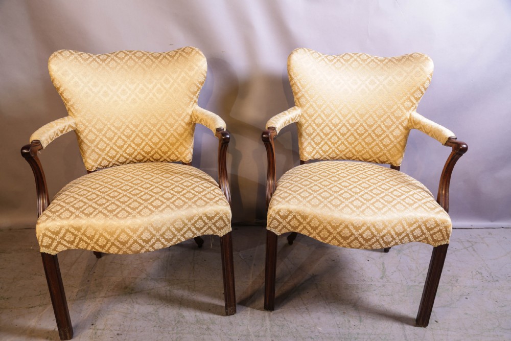 A pair of Georgian period mahogany armchairs upholstered in gold pattern damask fabric with swept timber arms.