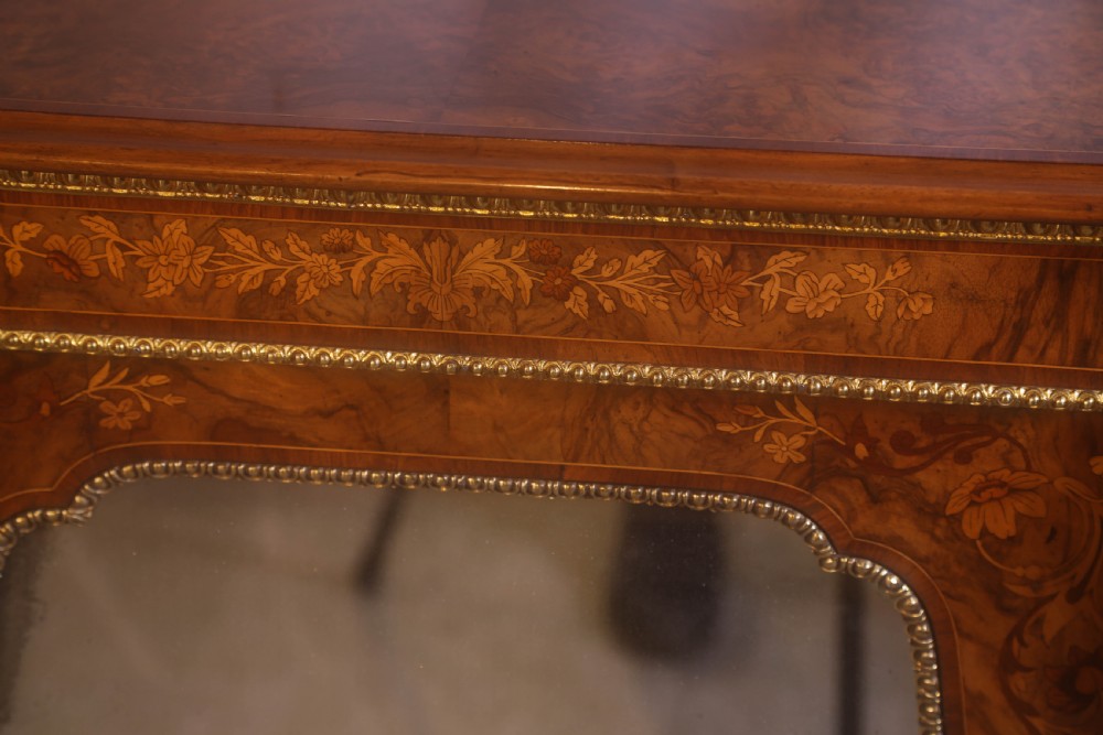 A Victorian burr walnut credenza featuring floral marquetry inlay, gilt-metal mounts, a central mirrored door, and curved glass side display compartments. View XII