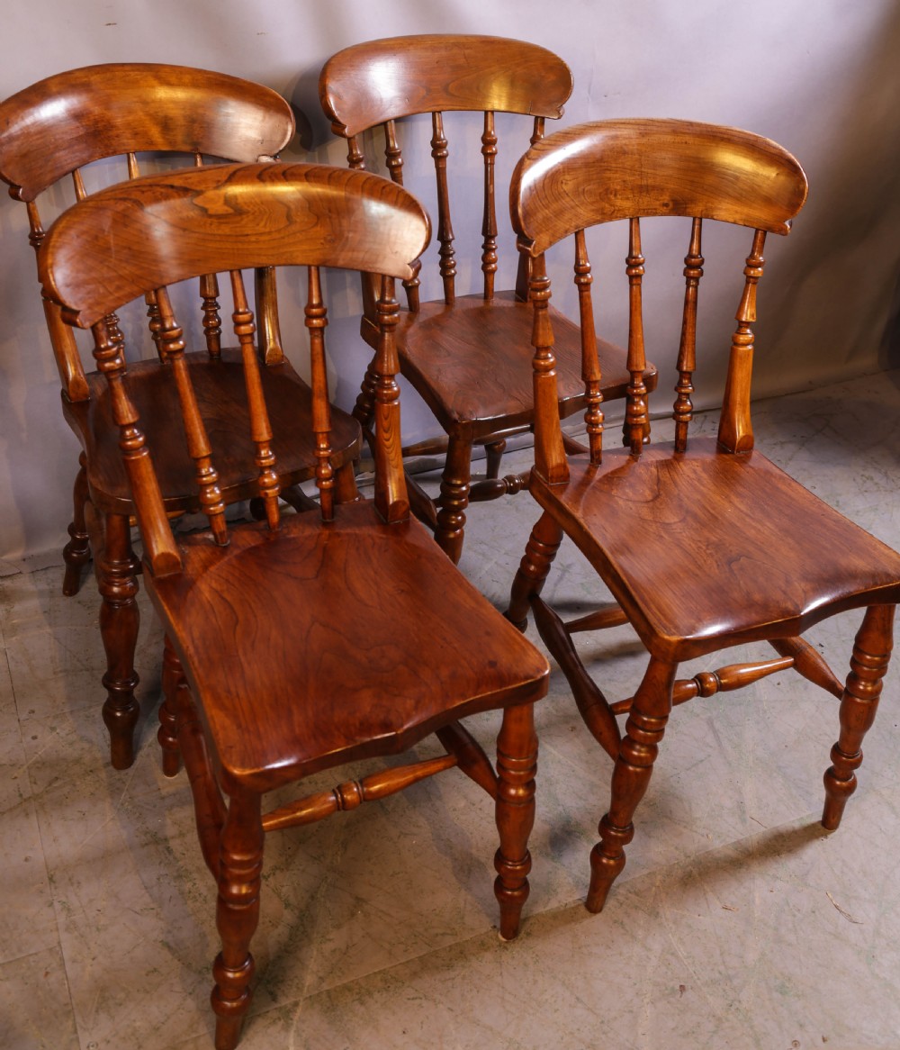 A set of four antique wooden kitchen chairs featuring rounded crest rails, turned back spindles, shaped solid seats, and turned legs. View II