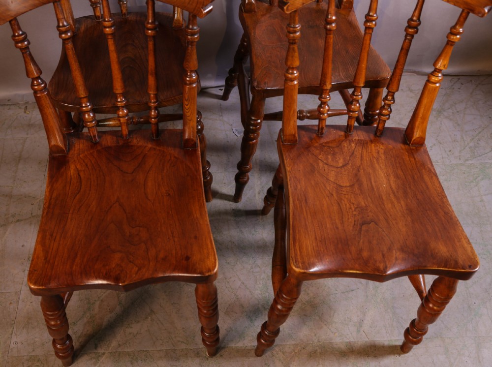 A set of four antique wooden kitchen chairs featuring rounded crest rails, turned back spindles, shaped solid seats, and turned legs. View III