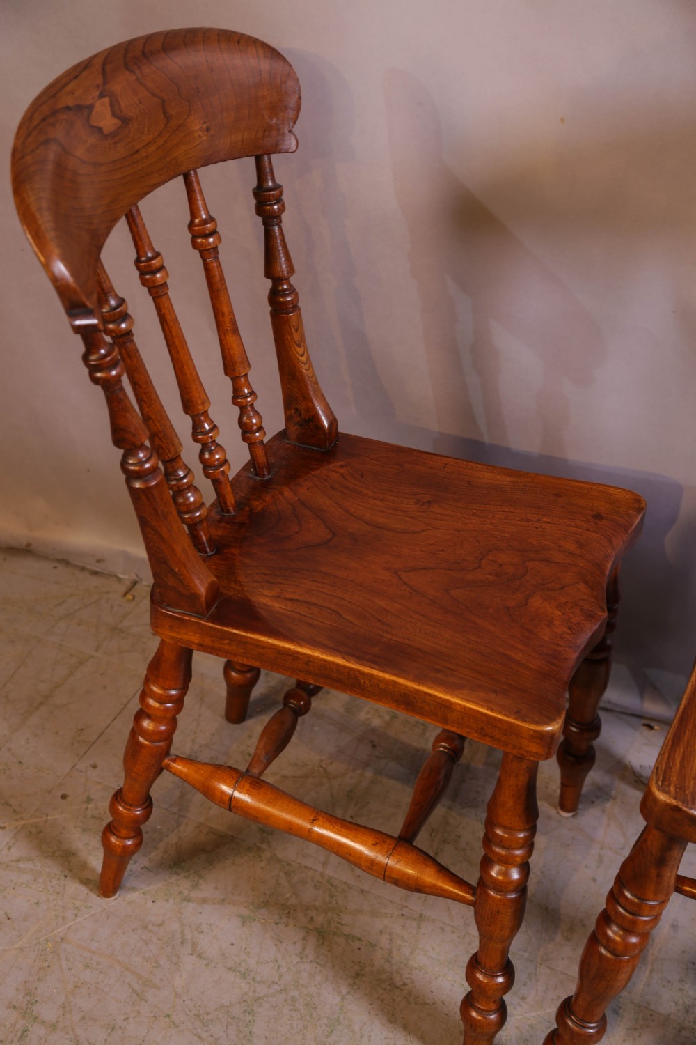 A set of four antique wooden kitchen chairs featuring rounded crest rails, turned back spindles, shaped solid seats, and turned legs. View IV