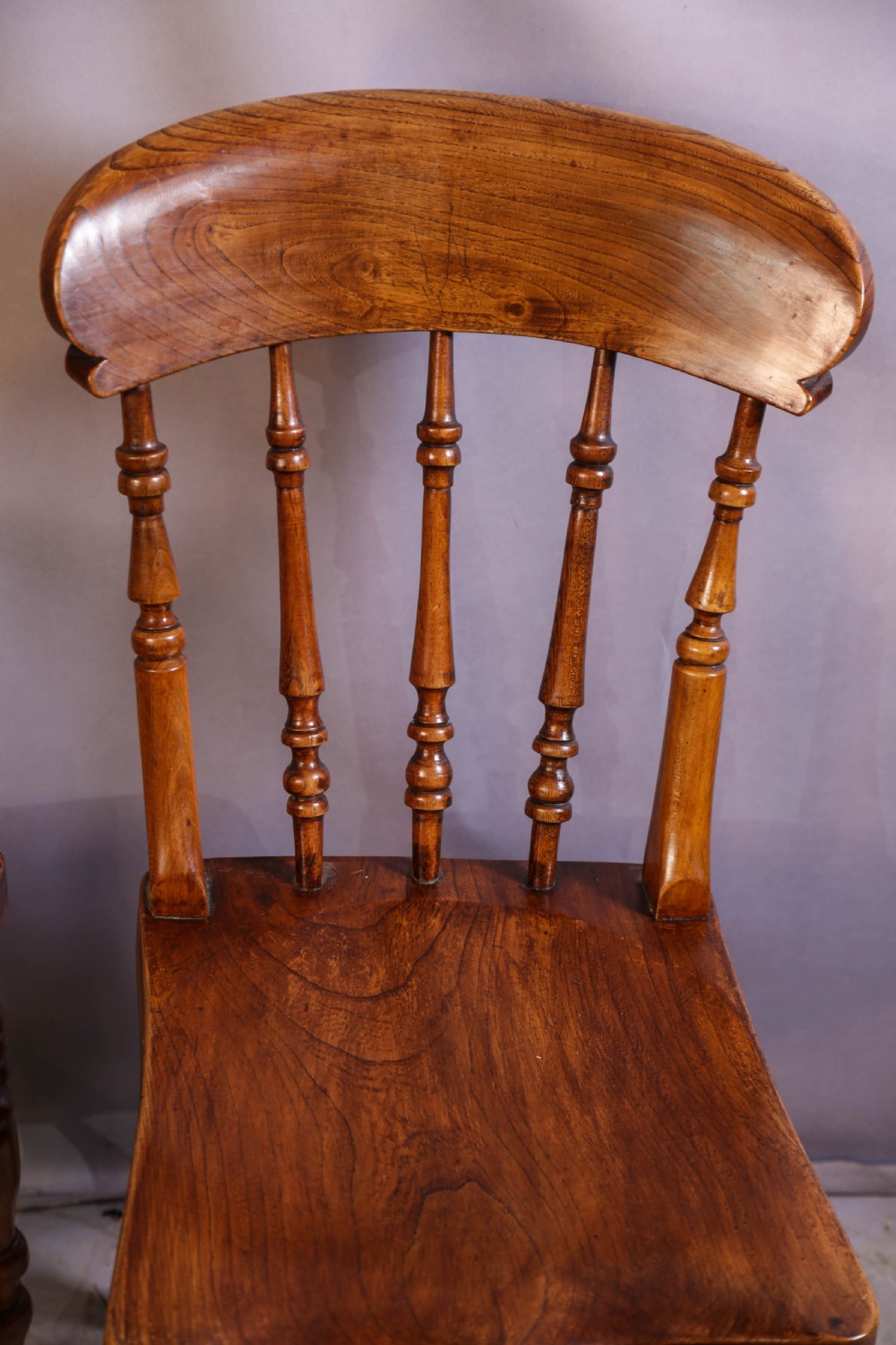 A set of four antique wooden kitchen chairs featuring rounded crest rails, turned back spindles, shaped solid seats, and turned legs. View VI