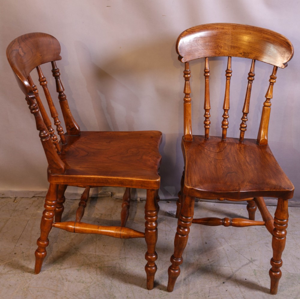 A set of four antique wooden kitchen chairs featuring rounded crest rails, turned back spindles, shaped solid seats, and turned legs. View VII