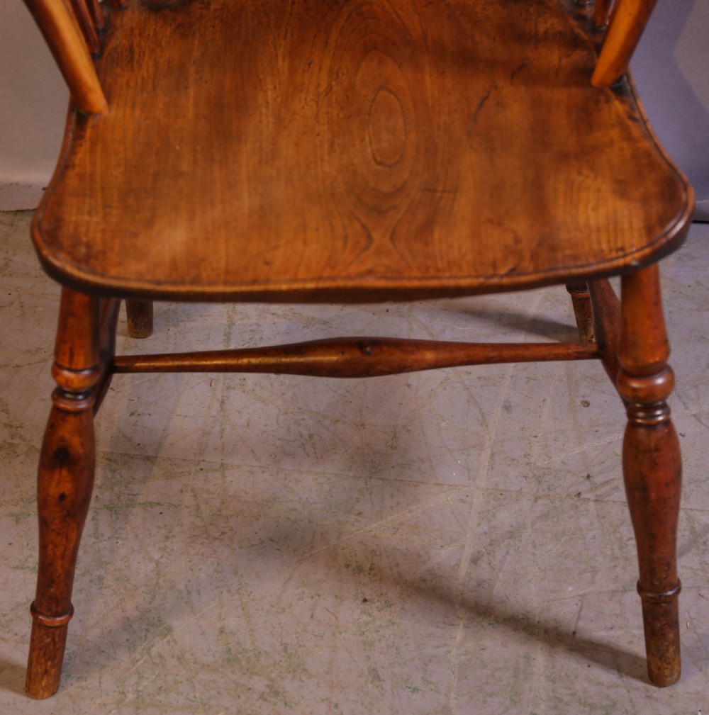 An antique Thames Valley yew wood Windsor armchair featuring a hoop back, central pierced wheel splat, contoured saddle seat, and turned legs. View IV