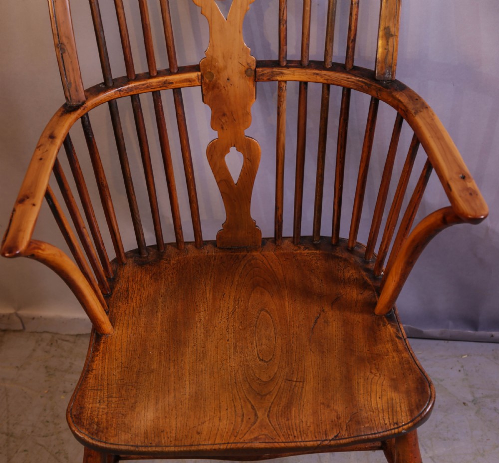 An antique Thames Valley yew wood Windsor armchair featuring a hoop back, central pierced wheel splat, contoured saddle seat, and turned legs. View V