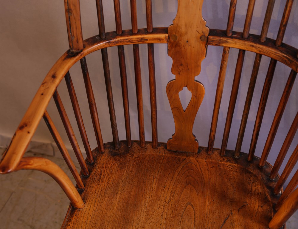 An antique Thames Valley yew wood Windsor armchair featuring a hoop back, central pierced wheel splat, contoured saddle seat, and turned legs. View VII