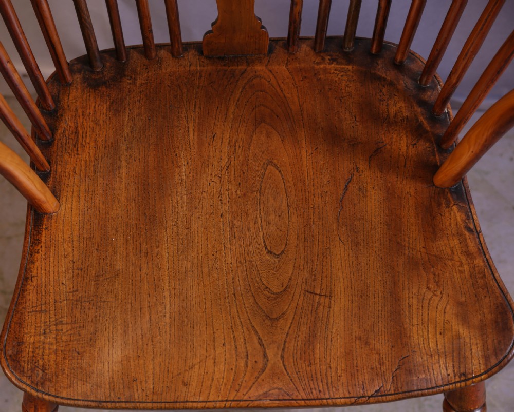 An antique Thames Valley yew wood Windsor armchair featuring a hoop back, central pierced wheel splat, contoured saddle seat, and turned legs. View IX