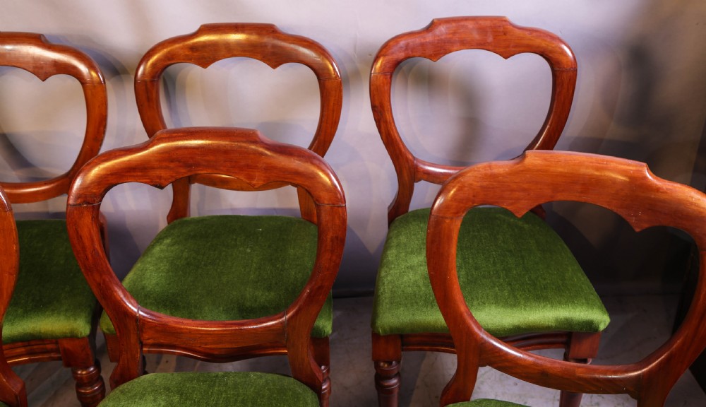 A set of eight Victorian mahogany balloon-back dining chairs with green velvet upholstered seats and turned front legs. View V