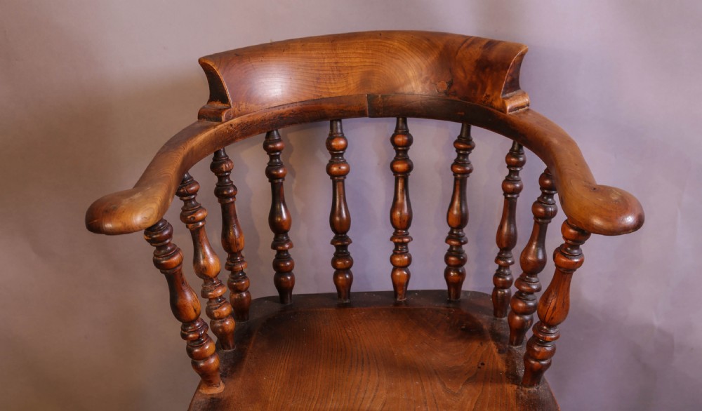 A Victorian captains chair made of polished yew wood featuring a curved crest rail, turned spindles, turned legs, and a solid shaped elm seat. View II