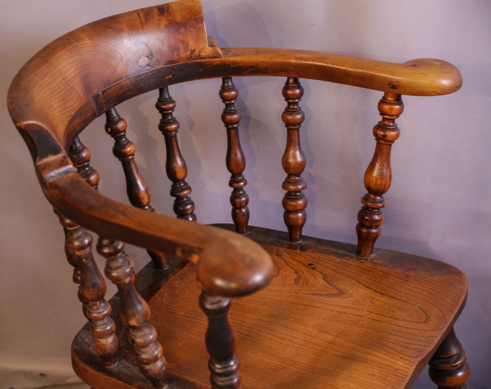 A Victorian captains chair made of polished yew wood featuring a curved crest rail, turned spindles, turned legs, and a solid shaped elm seat. View V