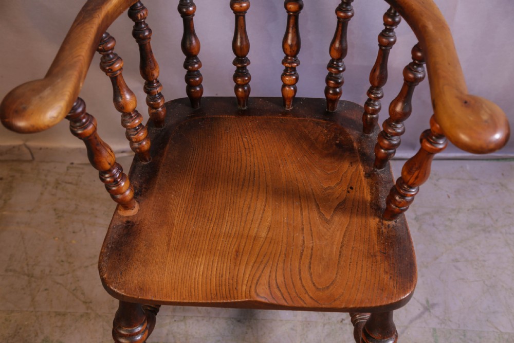 A Victorian captains chair made of polished yew wood featuring a curved crest rail, turned spindles, turned legs, and a solid shaped elm seat. View IX