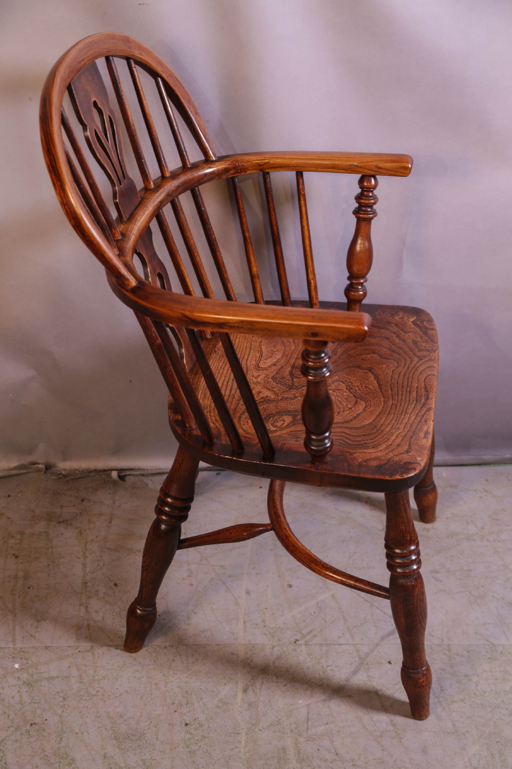 A wooden Windsor armchair featuring a steam-bent hoop back, pierced central splat, shaped elm seat, and turned legs. View III