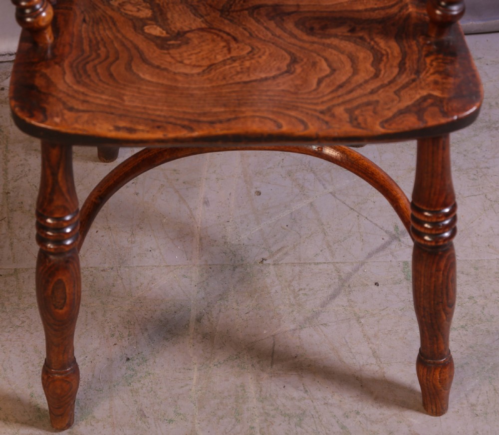 A wooden Windsor armchair featuring a steam-bent hoop back, pierced central splat, shaped elm seat, and turned legs. View V