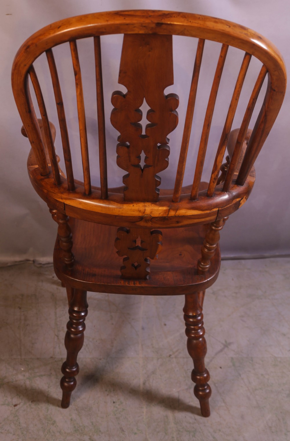 An antique yew wood high-back Windsor armchair featuring a pierced decorative splat, shaped pad arms, turned spindles, and a contoured wooden seat. View III