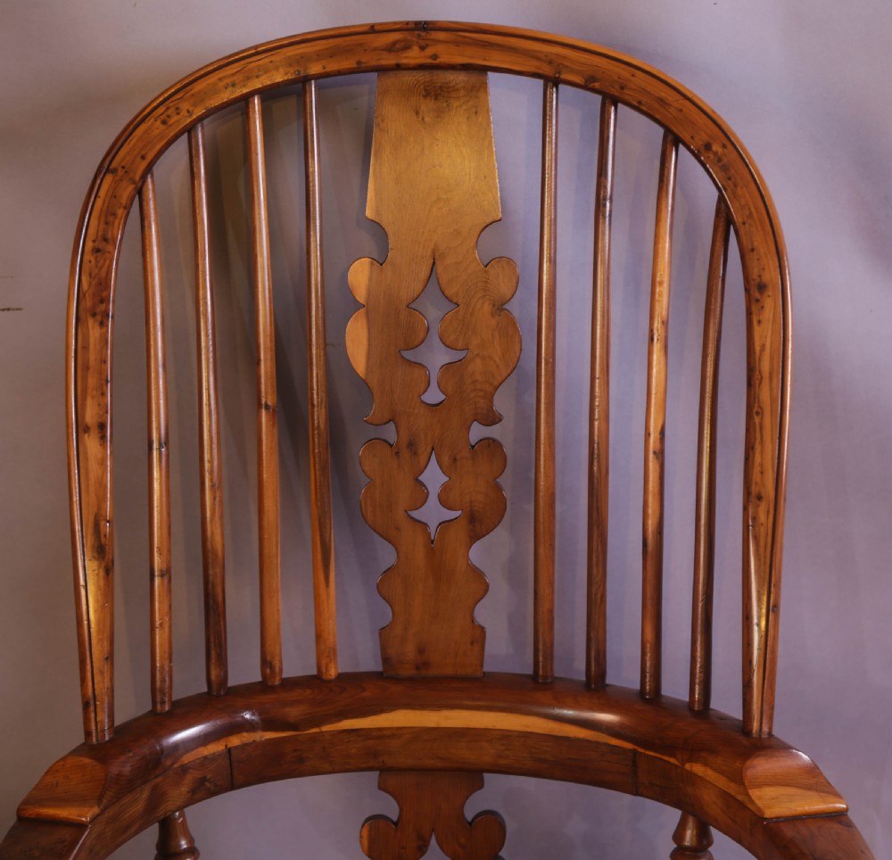 An antique yew wood high-back Windsor armchair featuring a pierced decorative splat, shaped pad arms, turned spindles, and a contoured wooden seat. View V
