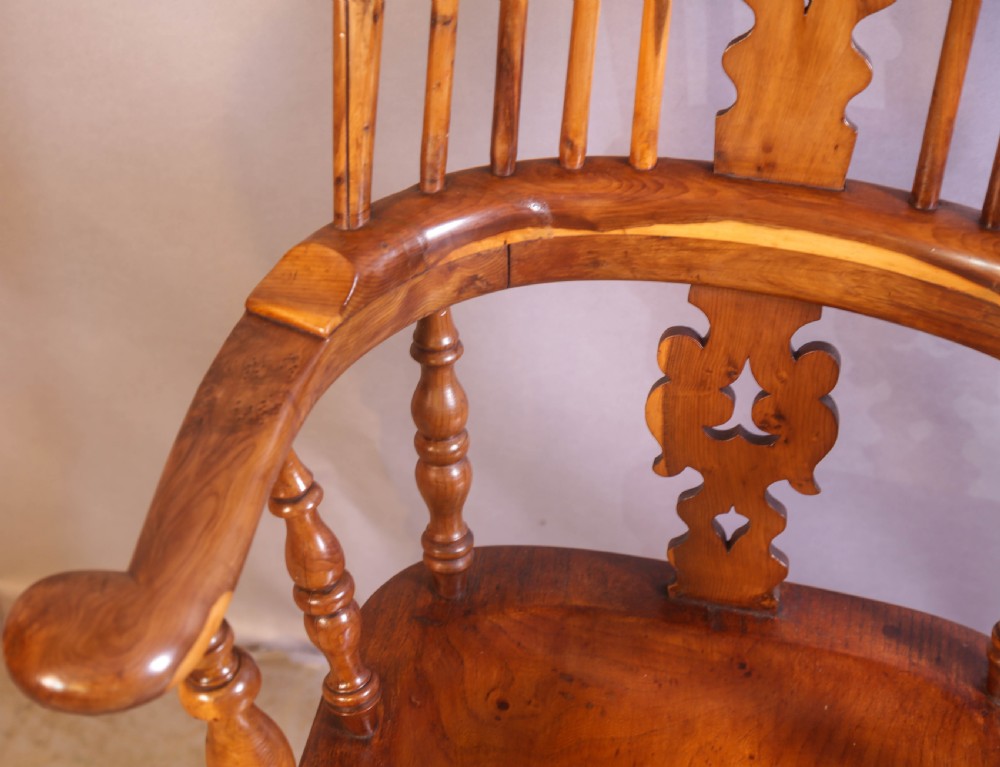 An antique yew wood high-back Windsor armchair featuring a pierced decorative splat, shaped pad arms, turned spindles, and a contoured wooden seat. View VII
