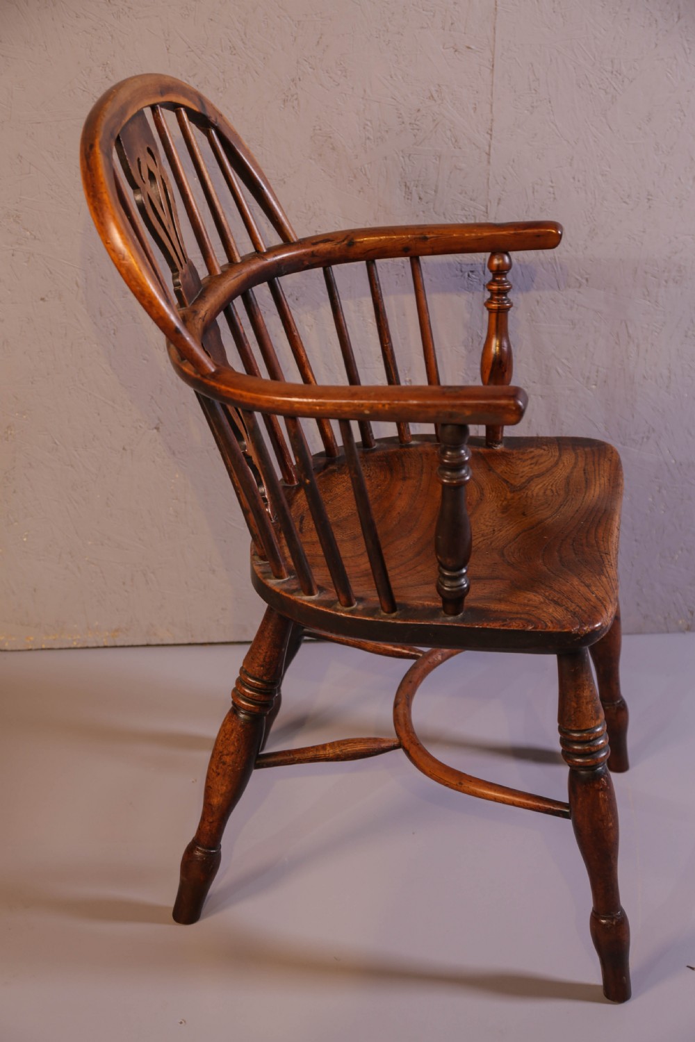 An antique yew wood low back Windsor chair featuring a contoured saddle seat, pierced splat back, turned spindles, and a curved stretcher connecting turned legs. View II