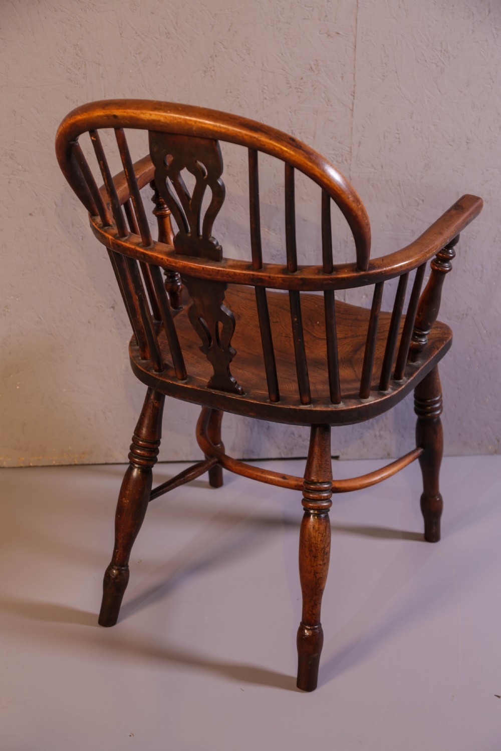 An antique yew wood low back Windsor chair featuring a contoured saddle seat, pierced splat back, turned spindles, and a curved stretcher connecting turned legs. View III