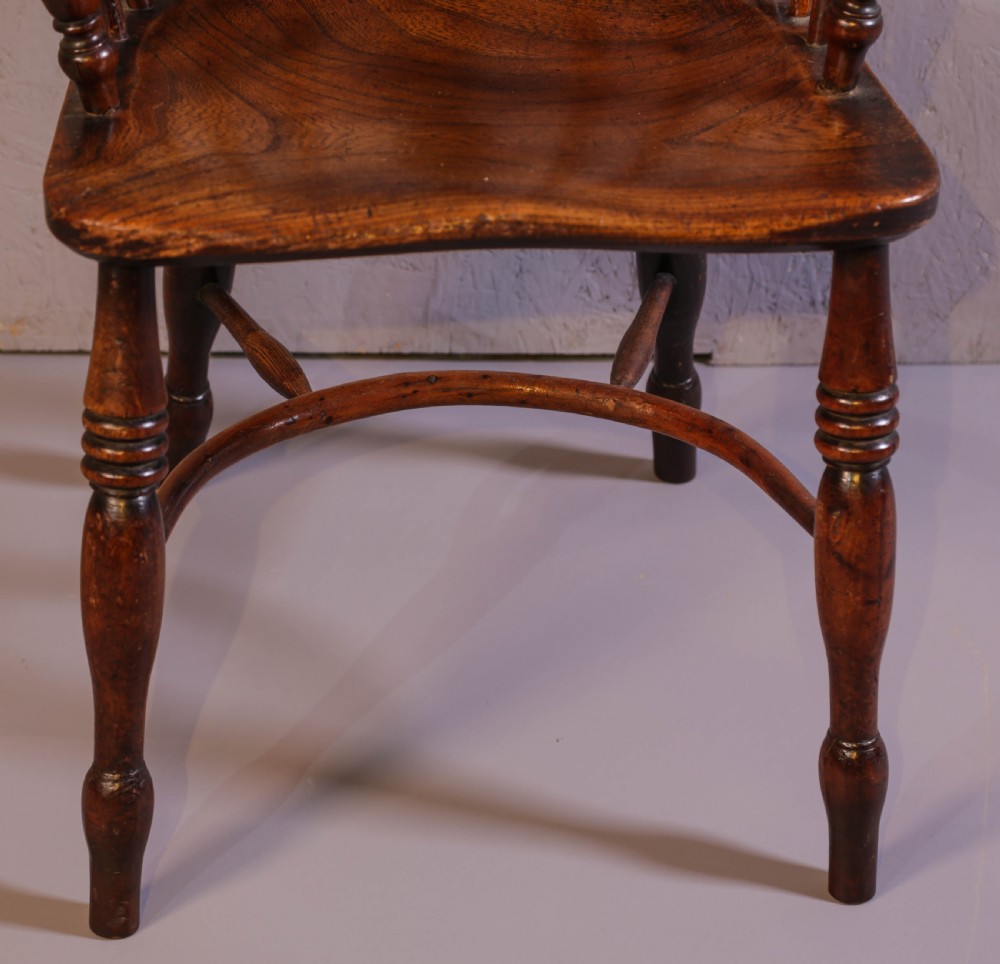 An antique yew wood low back Windsor chair featuring a contoured saddle seat, pierced splat back, turned spindles, and a curved stretcher connecting turned legs. View IV