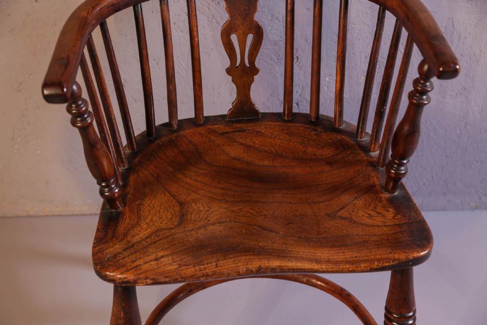 An antique yew wood low back Windsor chair featuring a contoured saddle seat, pierced splat back, turned spindles, and a curved stretcher connecting turned legs. View V