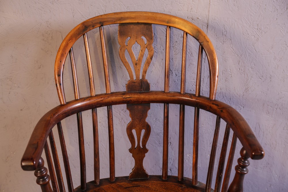 An antique yew wood low back Windsor chair featuring a contoured saddle seat, pierced splat back, turned spindles, and a curved stretcher connecting turned legs. View VI