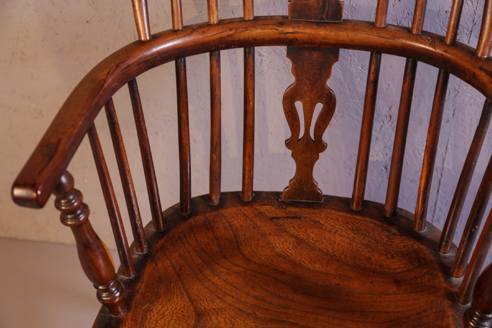An antique yew wood low back Windsor chair featuring a contoured saddle seat, pierced splat back, turned spindles, and a curved stretcher connecting turned legs. View VII