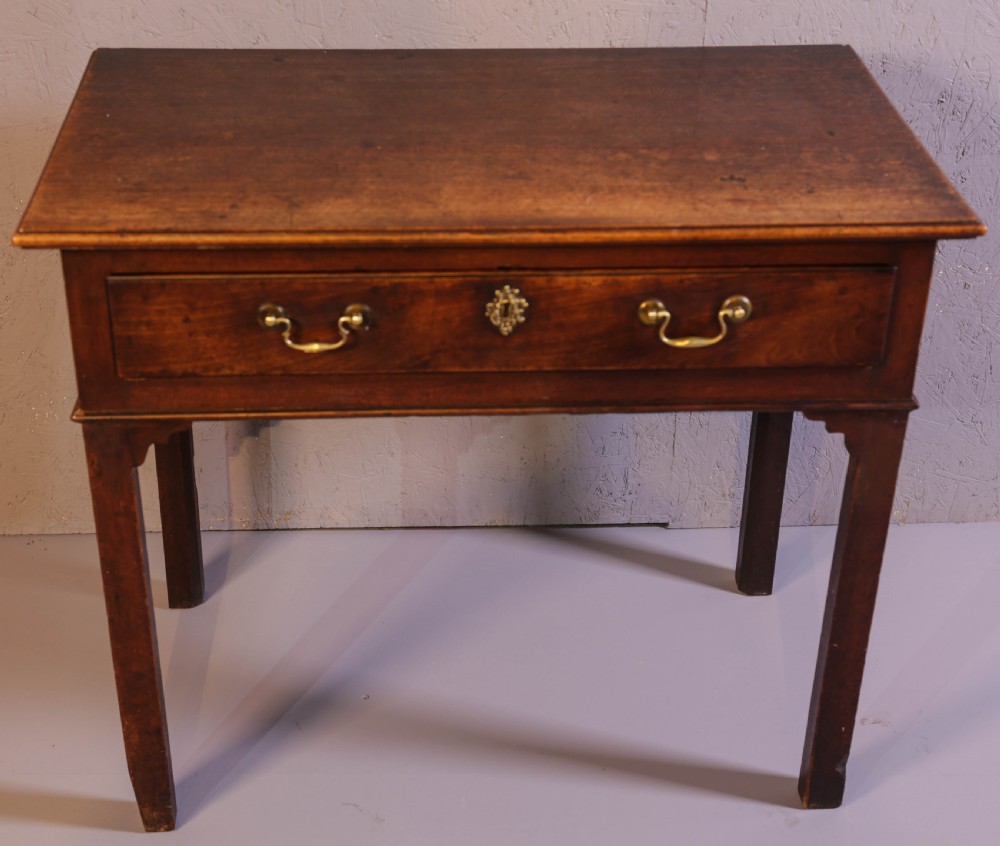 A dark Georgian mahogany side table featuring a single drawer with brass swan neck handles and square legs.