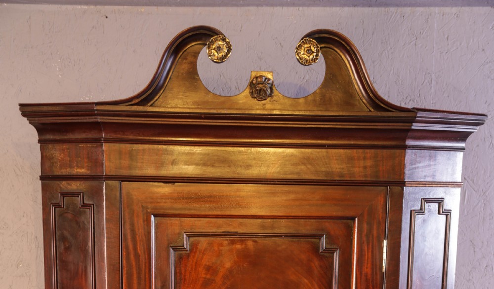 Georgian mahogany corner cupboard with a swan-neck pediment, carved gilt rosettes, and a fielded flame mahogany single door. View II