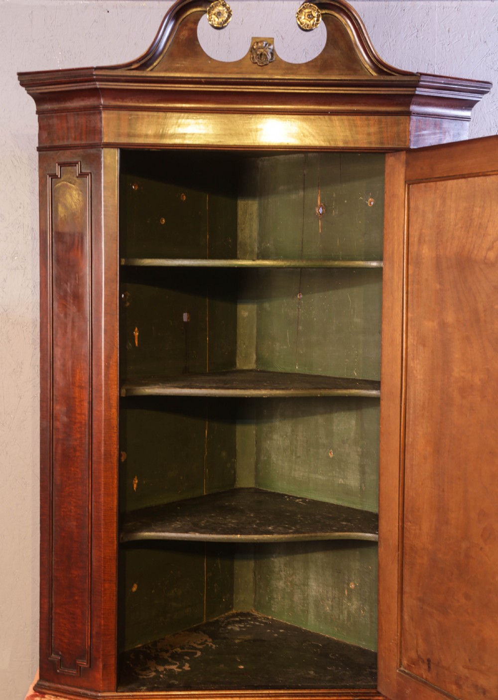 Georgian mahogany corner cupboard with a swan-neck pediment, carved gilt rosettes, and a fielded flame mahogany single door. View III