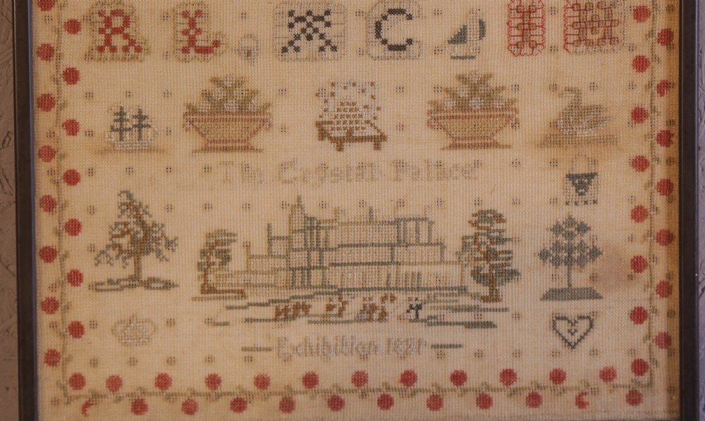 Framed 1851 Victorian needlework sampler featuring alphabets, numbers, and an embroidered depiction of the Crystal Palace on a linen ground. View IV