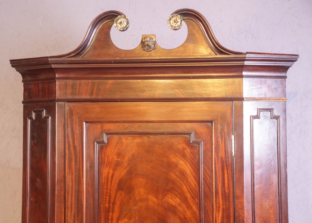 A Georgian mahogany corner cupboard featuring a swan-neck pediment with carved rosettes and a single flame mahogany panelled door. View III