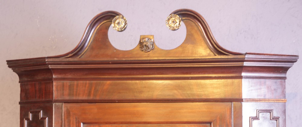 A Georgian mahogany corner cupboard featuring a swan-neck pediment with carved rosettes and a single flame mahogany panelled door. View IV